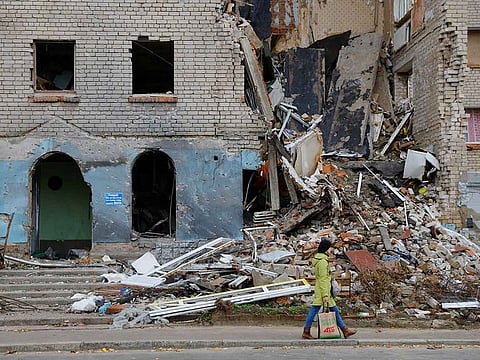 A woman walks past a building damaged in the course of Russia-Ukraine conflict in the town of Nova Kakhovka, Russian-controlled Ukraine, October 30, 2022.  