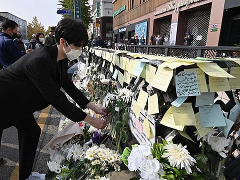 A mourner lays flowers at a makeshift memorial for the victims of the deadly Halloween crowd surge, outside a subway station in the district of Itaewon in Seoul on November 1, 2022.