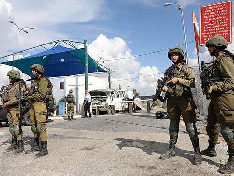 Israeli soldiers stand guard near a car damaged in a reported ramming attack at the Maccabim checkpoint in the West Bank, near Israel's central city of Modiin, on November 2, 2022.  