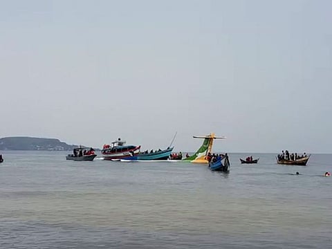 Rescuers in boats are seen around the tail fin of a crashed Precision Air passenger aircraft.