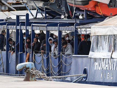 Migrants stand on the deck of the Humanity 1 rescue ship run by the German organization SOS Humanitarian, at harbor in the port of Catania, Sicily, southern Italy, on Sunday.