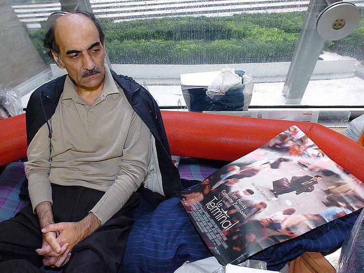 In this file photo taken on August 12, 2004 Mehran Karimi Nasseri looks at a poster of the movie inspired by his life, in the terminal 1 of Paris Charles De Gaulle airport.