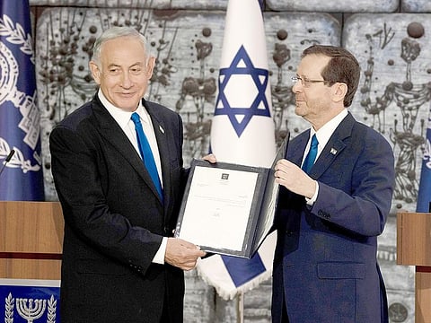 Israel's Likud Party leader Benjamin Netanyahu, left, and Israel's President Isaac Herzog pose on the podium after Herzog assigned Netanyahu the task of forming a government, in Jerusalem, on Sunday, November 13, 2022. 
