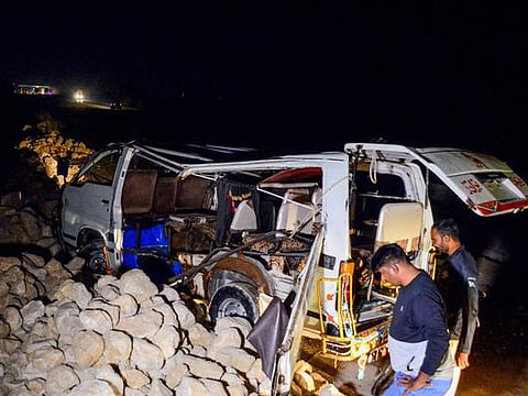 A policeman stands beside a damaged passenger mini bus after an overnight accident in Sehwan of Sindh province on November 18, 2022.  