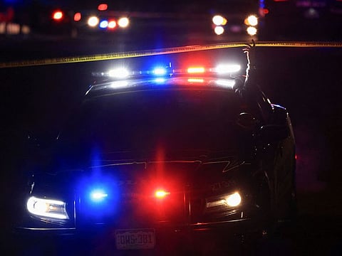 A police officer lifts barricade tape while in their vehicle as they respond to a mass shooting at the Club Q nightclub.