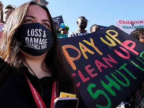 A demonstrator holds a sign that reads "pay up clean up shut up" during a protest at the COP27 UN Climate Summit, Saturday, Nov. 12, 2022, in Sharm Al Sheikh, Egypt. 