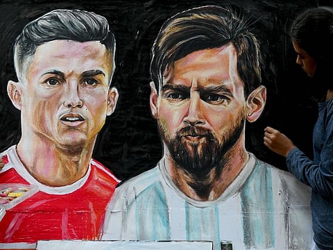 An art school student gives the final touches to a painting of football stars Cristiano Ronaldo (left) and Lionel Messi in Mumbai.