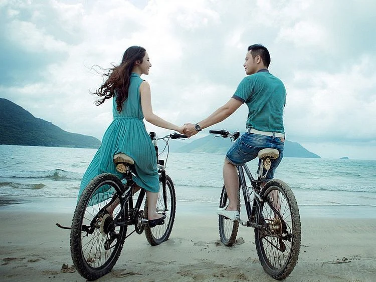 Couple on a bicycle holding hands
