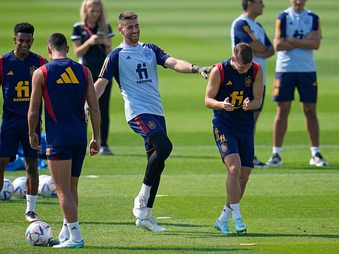 Spain goalkeeper Unai Simon (centre) jokes with Dani Olmo (right) during a training session at Qatar University, in Doha, Qatar. Spain will play its first match in Group E in the World Cup against Costa Rica tomorrow.
