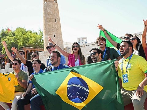 Football fans cheer with a Brazil’s flag at the Souq Waqif during the Qatar 2022 World Cup football tournament in Doha on November 23, 2022. Brazil face Serbia at the Lusail Stadium Thursday night, in their first match of the torunament. 