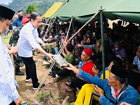 Indonesian President Joko Widodo distributes sarong to people who are sheltered at a temporary tent during his visit to the locations affected by the Monday's earthquake in Cianjur, West Java province, Indonesia, November 24, 2022.