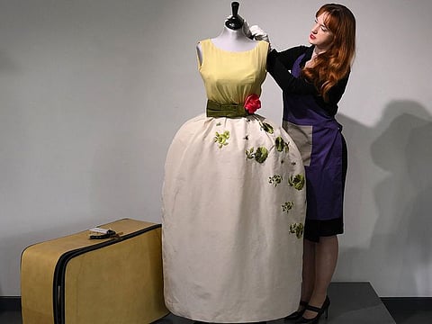 An employee poses with a Christian Dior dress worn by actress Elizabeth Taylor, and recently discovered with other dresses in a suitcase, ahead of their sale at Kerry Taylor Auctions, in London.