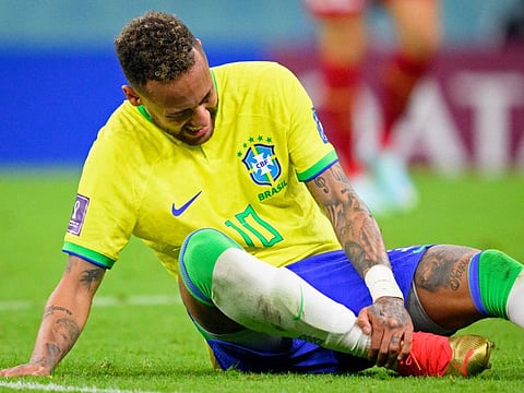 Brazil's Neymar grabs his ankle after an injury during the World Cup group G soccer match between Brazil and Serbia, at the the Lusail Stadium in Lusail, Qatar on Thursday, Nov. 24, 2022. (Laurent Gillieron/Keystone via AP)