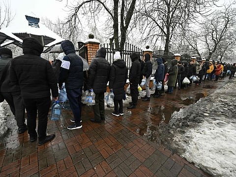 Local residents queue for access to a water pump in a park to fill plastic bottles in Kyiv, on November 24, 2022.  
