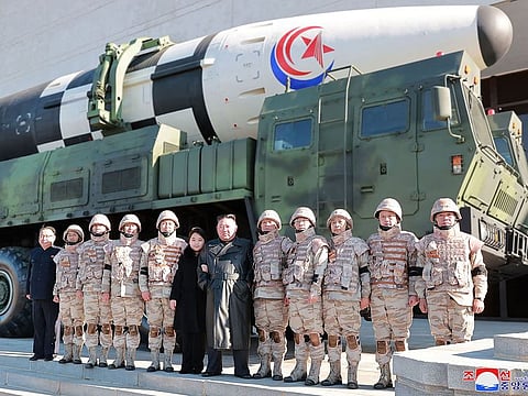 This undated picture released by KCNA on November 27, 2022 shows North Korea's leader Kim Jong Un and his daughter posing with soldiers who contributed to the test-firing of the new intercontinental ballistic missile (ICBM), at an unknown location in North Korea. 