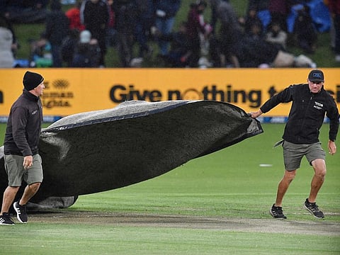 Ground staff cover the cricket pitch as rain stops the play during the third and final one-day international cricket match between New Zealand and India at Hagley Oval in Christchurch.