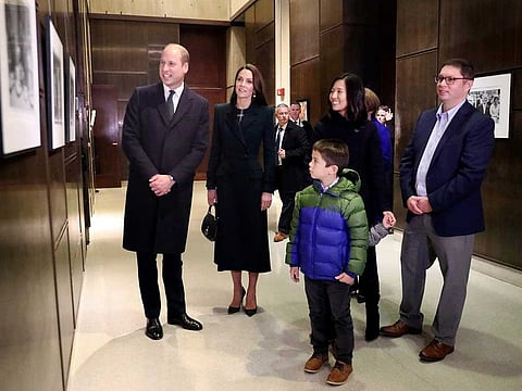 Boston Mayor Michelle Wu, right, and her family show photographs of the Queen Elizabeth II's visit in 1976, during the visit of Britain's Prince William and Kate, Princess of Wales, to Boston City Hall on Wednesday, Nov. 30, 2022, in Boston. The Prince and Princess of Wales are making their first overseas trip since the death of Queen Elizabeth II in September.  (Nancy Lane/The Boston Herald via AP, Pool)