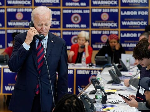 President Joe Biden speaks on the phone while visiting a phone bank at International Brotherhood of Electrical Workers Local 103, Friday, Dec. 2, 2022, in Boston. 