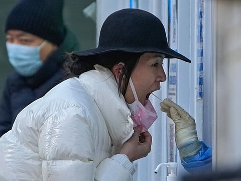 A woman has her routine COVID-19 throat swab at a testing site in Beijing, on Dec. 4, 2022.  