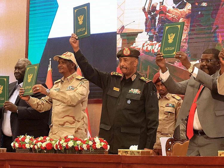 Sudan's Army chief Abdul Fattah Al Burhan (centre) and paramilitary commander Mohammad Hamdan Dagalo (2nd left) lift documents alongside civilian leaders following the signature of an initial deal aimed at ending a deep crisis caused by last year's military coup, in the capital Khartoum on December 5, 2022.  
