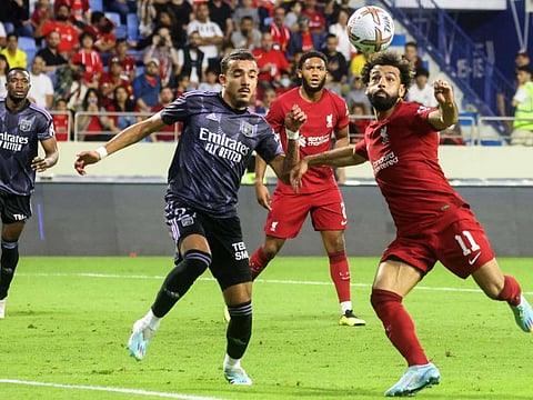 Lyon's French defender Malo Gusto (left) attempts to block a kick from Liverpool's Egyptian striker Mohamed Salah during the Dubai Super Cup 2022 at Al Makrtoum stadium, Dubai, UAE. 