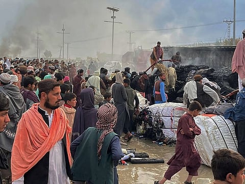 People gather beside a burnt truck caused by Afghan forces shelling, in Chaman, a town in Pakistan's southwestern along Afghan border, Sunday, Dec. 11, 2022.