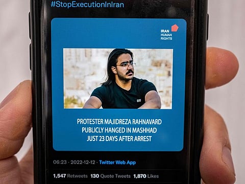 A person in the Cypriot capital Nicosia checks a mobile phone on December 12, 2022, displaying a Tweet about the execution announced by Iranian authorities of Majidreza Rahnavard, the second capital punishment linked to nearly three months of protests.