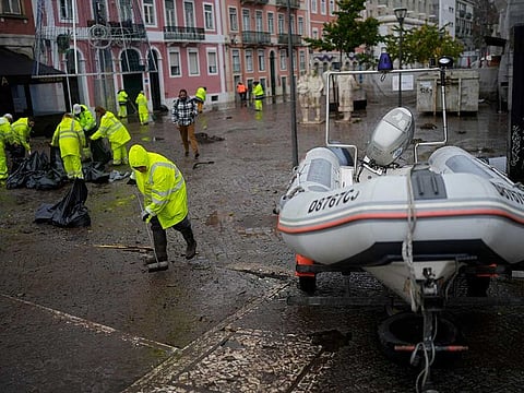 Municipal workers clean a street that was flooded overnight in Alges, just outside Lisbon, Tuesday, Dec. 13, 2022. An Atlantic storm slammed into the Iberian peninsula, leaving behind a trail of destruction Tuesday, especially in the Portuguese capital Lisbon, before moving eastward into Spain. 