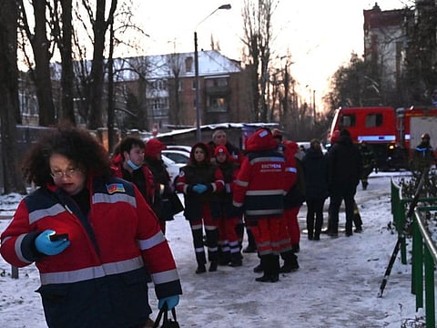 Rescuers gather close to a partially destroyed administrative building after a drone strike on the Ukrainian capital Kyiv on December 14, 2022.