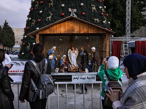 People take pictures of the Christmas tree and nativity scene in Manger Square, outside to the Church of the Nativity, traditionally believed by Christians to be the birthplace of Jesus Christ, ahead of Christmas, in the West Bank city of Bethlehem.