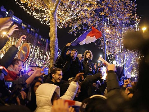 A football fan holds the French flag as he celebrates after France's victory over Morocco in the Qatar 2022 World Cup semi-final, on the Champs-Elysees in Paris on December 14, 2022. 