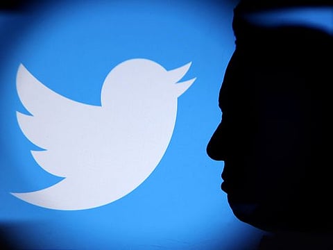 Elon Musk photo and Twitter logo are seen through magnifier in this illustration. 