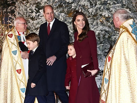 Britain's Prince William, Prince of Wales, Kate, Princess of Wales, Prince George and Princess Charlotte attend the 'Together At Christmas' carol service at Westminster Abbey, in London, Thursday, Dec. 15, 2022.   Prince William's godmother has met to offer her sincere apologies to a woman over "unacceptable" comments she had made about her race and nationality at an official royal reception last month, Buckingham Palace said on Friday.