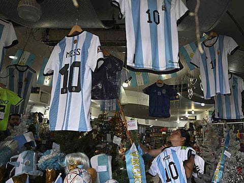 A woman organizes t-shirts of the Argentine national football team inside a store ahead of the Qatar 2022 World Cup final between Argentina and France in Buenos Aires.