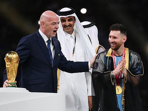 Argentina's Lionel Messi holds up the trophy flanked by FIFA President Gianni Infantino and the Emir of Qatar Sheikh Tamim bin Hamad Al Thani after winning the World Cup final soccer match between Argentina and France at the Lusail Stadium in Lusail, Qatar, Sunday, Dec.18, 2022.