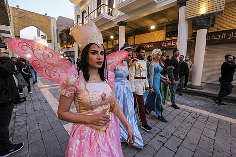 Costumed performers walk along the reopened and renovated Al Mutanabbi street, the historic heart of the book trade and an outlet for writers and intellectuals, in the centre of Iraq's capital Baghdad on December 25, 2021. 