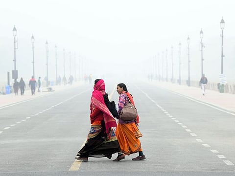 Women cross the road amid dense fog on a cold winter morning, at Kartavya Path, in New Delhi on Monday, Dec 26, 2022.