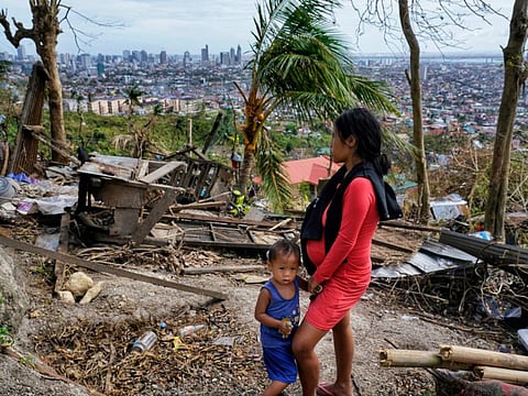 Alona Nacua, right, stands beside her son as she looks at their damaged house due to Typhoon Rai in Cebu city, central Philippines on Christmas Day. 