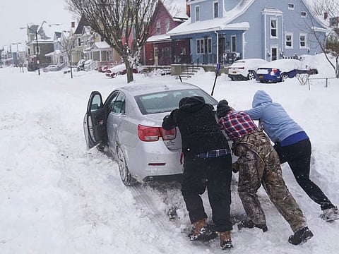 Neighbours help push a motorist stuck in the snow in Buffalo, N.Y., on Monday, Dec. 26, 2022.