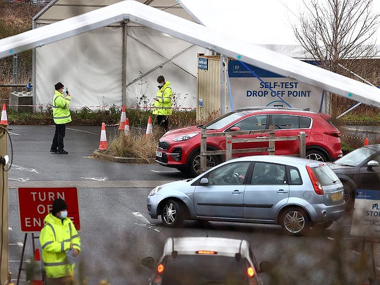 NHS workers assist members of the public as they drive into a COVID-19 test centre close to the Royal Surrey County hospital in Guildford, southern England.