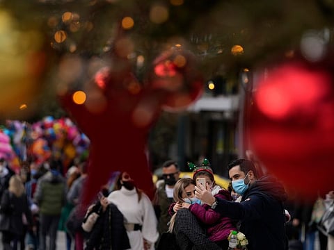 A family takes a selfie in front of Christmas tree at Syntagma square, in Athens, Greece, on December 30, 2021. Greece had a record number of new daily coronavirus cases for the third consecutive day Wednesday, and authorities have announced they were moving up restrictions meant to go into place in the new year to Thursday, in an effort to limit its spread. 