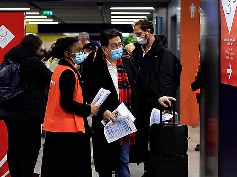 Passengers arriving from China wait in front of a COVID-19 testing area set at the Roissy Charles de Gaulle airport, north of Paris, Sunday, Jan. 1, 2023. 