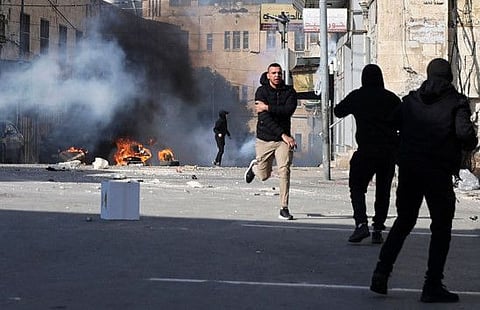 A Palestinian protester runs back following an injury amid clashes with Israeli security forces deploying during a raid in the old city of Nablus, on December 30, 2022. 
