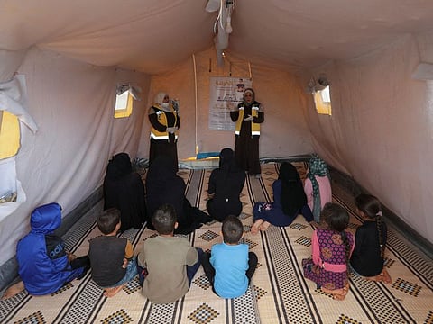 Civil defence members talk to internally displaced Syrians during a cholera awareness campaign, at a camp in northern rebel-held Idlib.