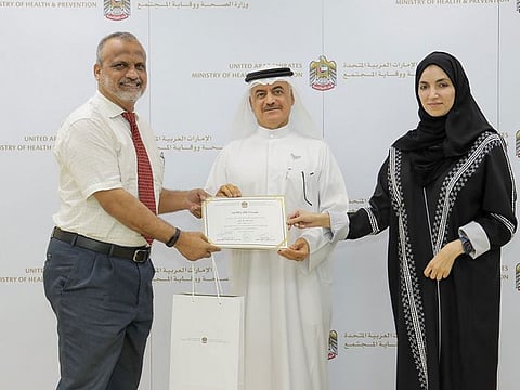 Dr. Amin Hussein Al Amiri, assistant undersecretary for the MoHAP’s Health Regulation Sector, honouring a retiree from the MInistry of Health and Prevention along with another official.