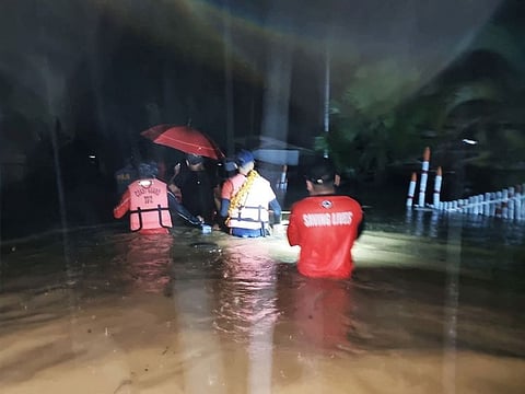 Members of the Philippine Coast Guard wade through a flooded street during a rescue operation, in Isabela, Basilan province.