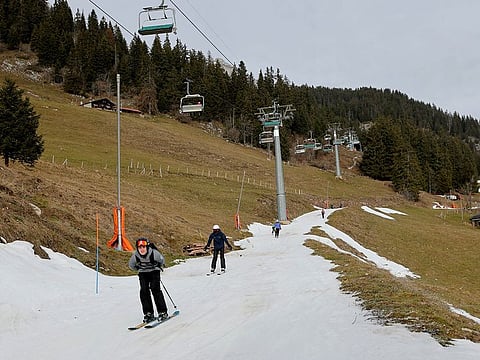 Skiers pass on a small layer of artificial snow amid warmer-than-usual winter temperatures in the Alps in Leysin, Switzerland.