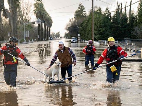 San Diego firefighters help Humberto Maciel rescue his dog  from his flooded home in Merced, California, on January 10, 2023.