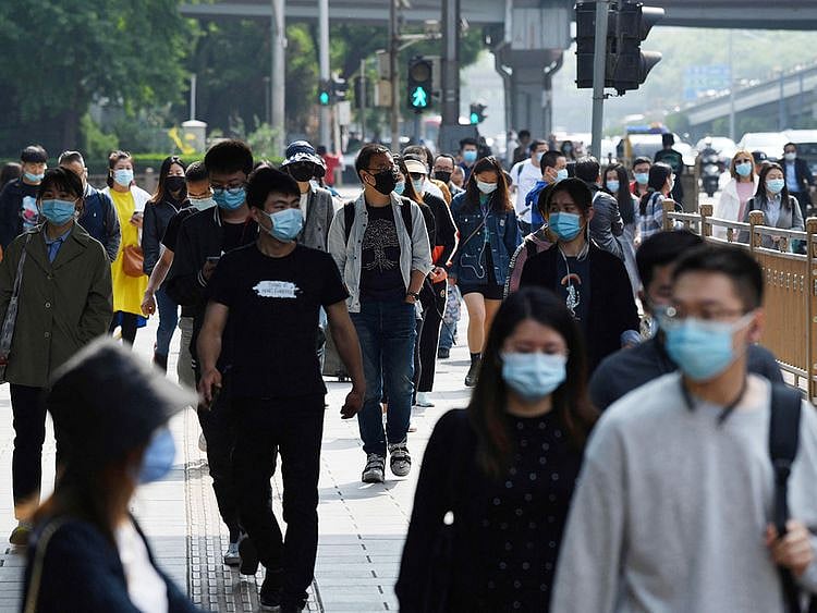 Commuters walk on a sidewalk during the morning rush hour in Beijing