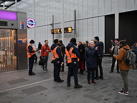 Commuters speak to staff members as barriers block the entrance to Elizabeth Line at Paddington station in London on January 12, 2023 amid a new strike by rail workers.